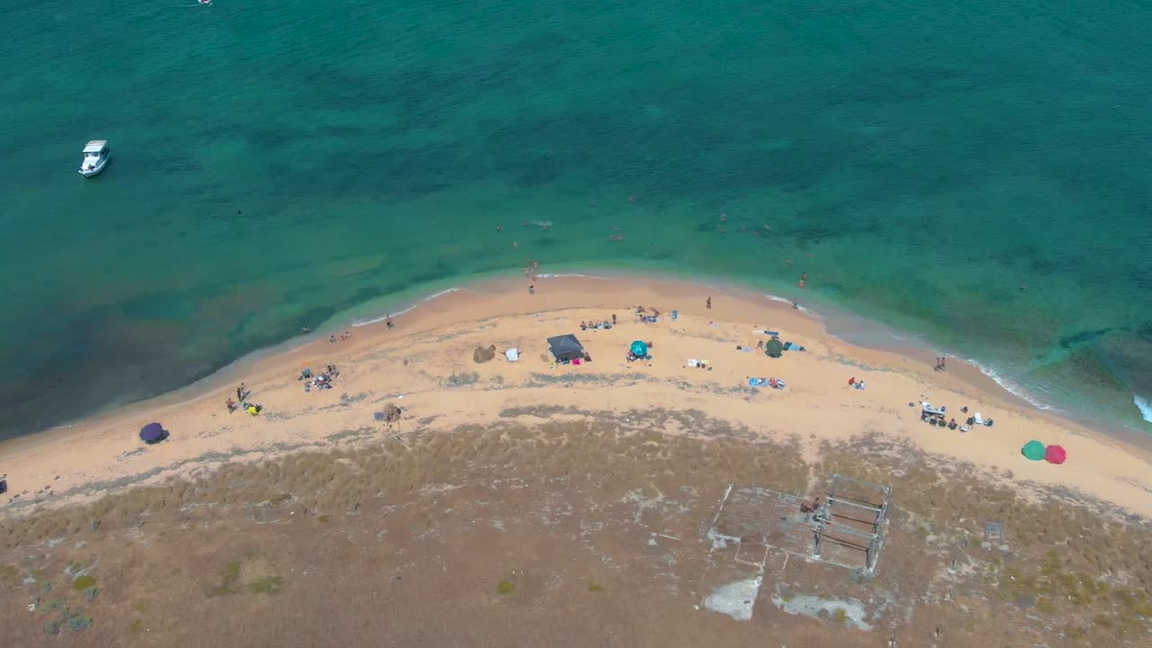 Aerial view of Rabbit Island's turquoise waters, Tripoli. Swimmers and boats dot the Mediterranean's crystal clear surface. 4K drone footage