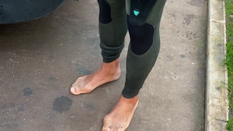 front view of active young male surfer legs wearing wet suit on the park in front a beach, cascais