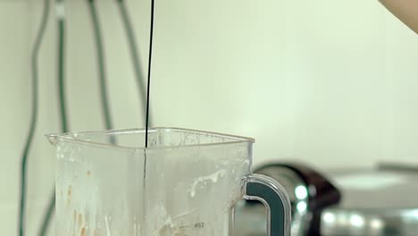 cook pours hot chocolate into the mixer with a cocktail