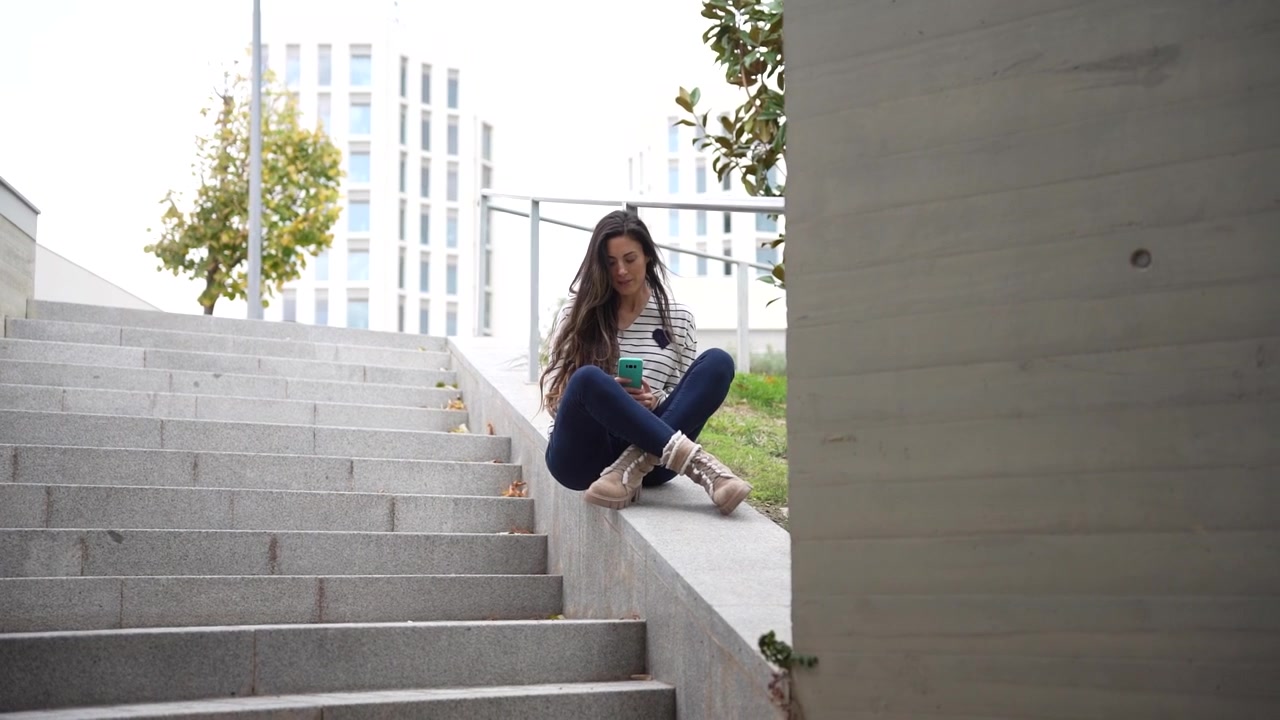 Una joven disfruta deliciosamente de una buena taza de café mientras se relaja en unas escaleras urbanas.