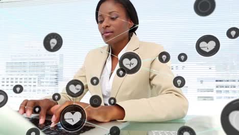 Animation-of-network-of-digital-icons-over-african-american-businesswoman-using-computer-at-office