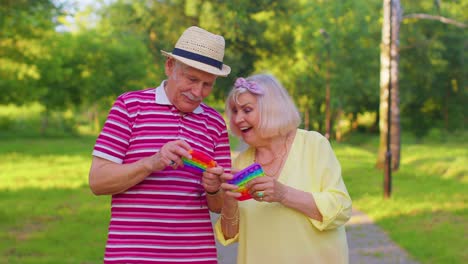 Älteres-Stilvolles-Paar-Großmutter-Großvater-Quetscht-Anti-Stress-Push-Pop-it-populäres-Spielzeugspiel