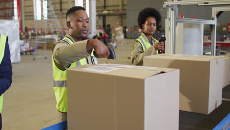 diverse male and female workers wearing safety suits and scanning boxes in warehouse