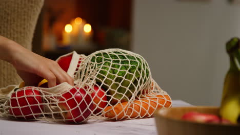 close up of woman unpacking bag of fresh healthy fruit and vegetables onto counter in kitchen 3