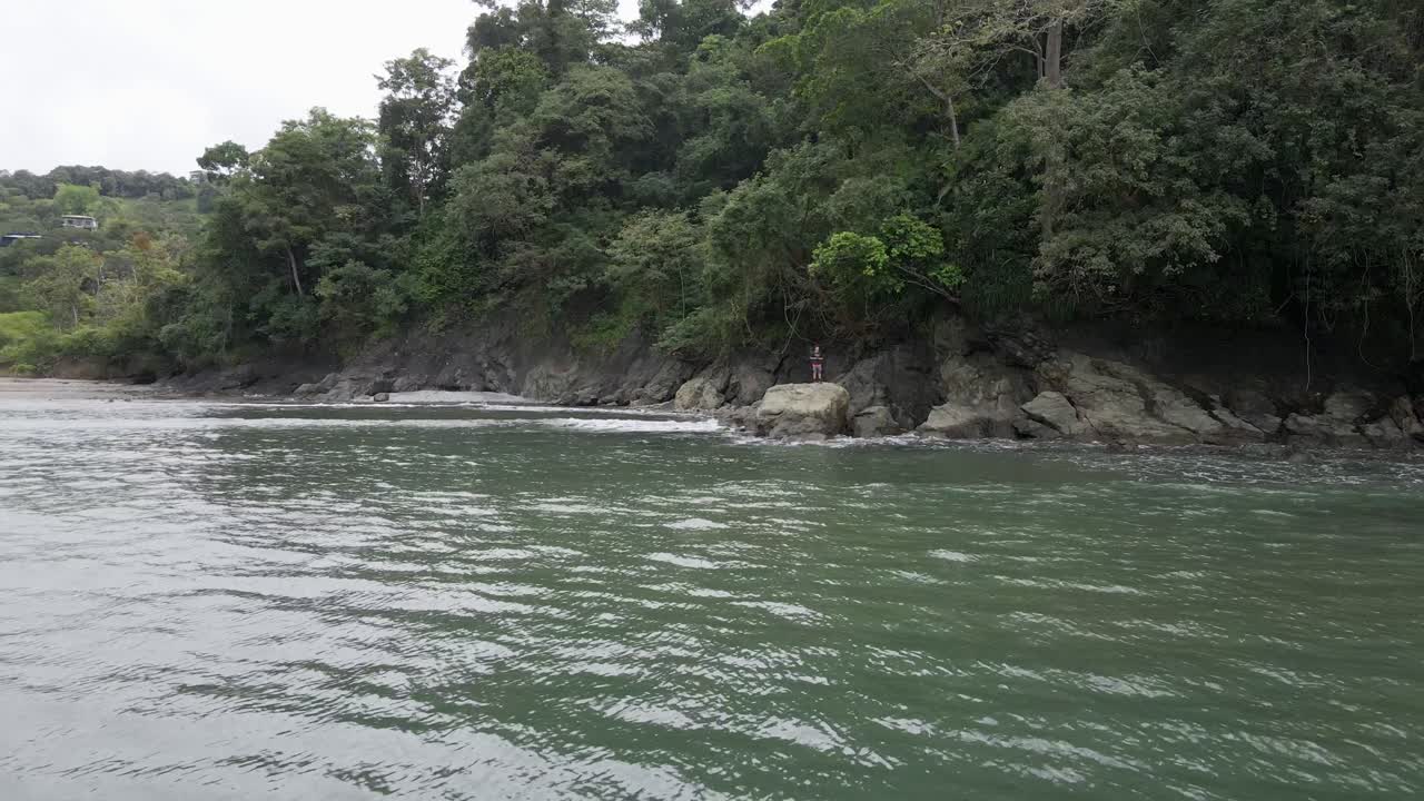 Giovane turista in piedi sulla costa rocciosa della tropicale Playa La Vaca vicino a Quepos, Costa Rica
