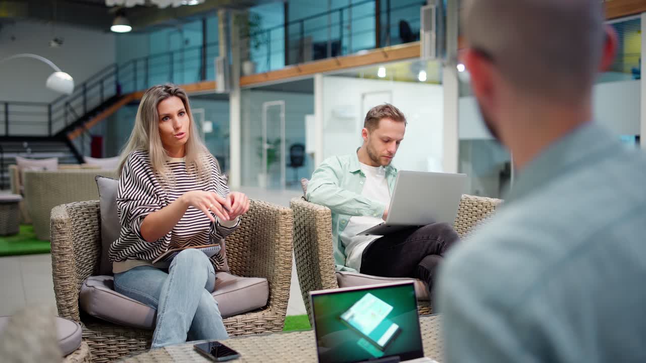 fotografía de seguimiento de un equipo de negocios de tres personas sentados en una sala de oficinas y discutiendo la estrategia de marketing en una reunión. gerente femenina explicando ideas, colegas masculinos trabajando en computadoras portátiles y escuchando