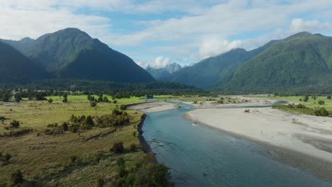 aerial drone flight over remote wilderness of southern alps mountainous landscape with braided river on the wild and rugged west coast of south island, new zealand aotearoa