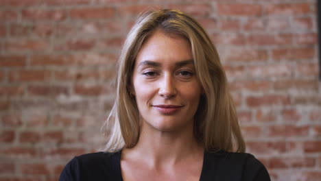 Portrait-Of-Smiling-Caucasian-Woman-Standing-Against-Brick-Wall-In-Coffee-Shop