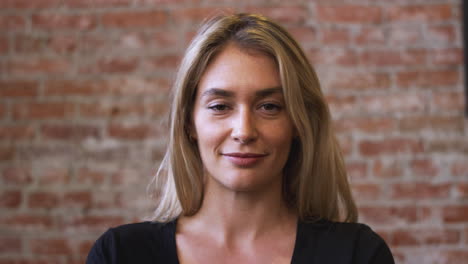 portrait of smiling caucasian woman standing against brick wall in coffee shop