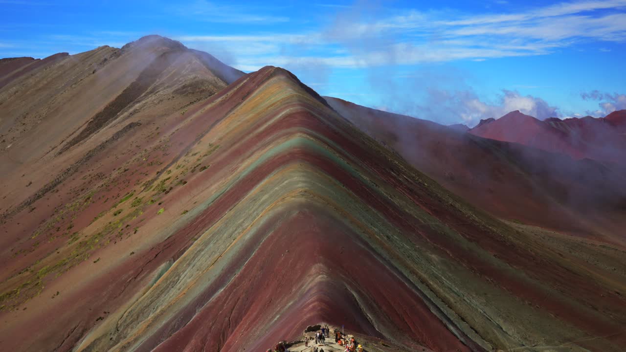 Montagna Arcobaleno Vinicunca delle Ande peruviane, Perù, con strato di nebbia bassa, paesaggio naturale della catena del Vilcanota, collina a sette strati colorati e a strisce, mattina di sole, cielo azzurro e nuvole, Sud America. Zoom.