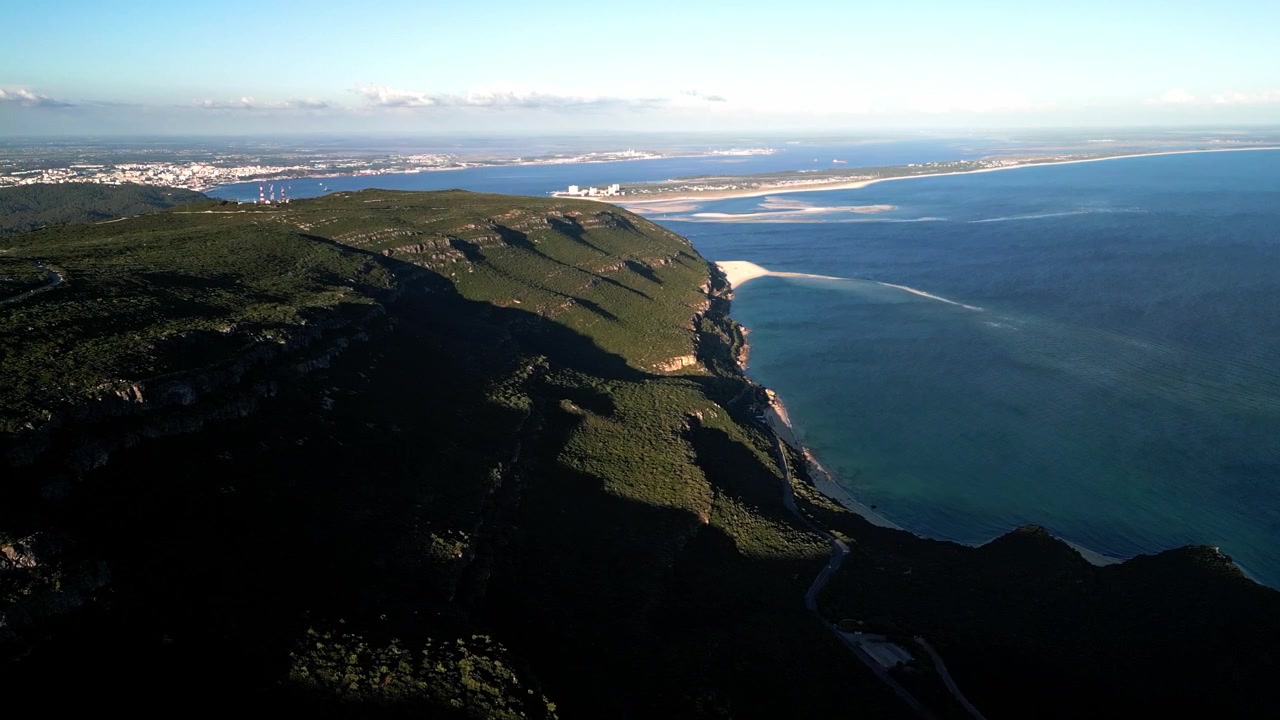 Vista aerea che sorvola scogliere costiere verdi con l'oceano blu e le spiagge sottostanti.