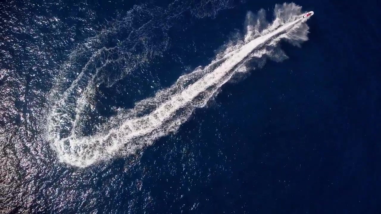 Motoscafo che fa una virata mentre naviga in acque marine blu scintillanti