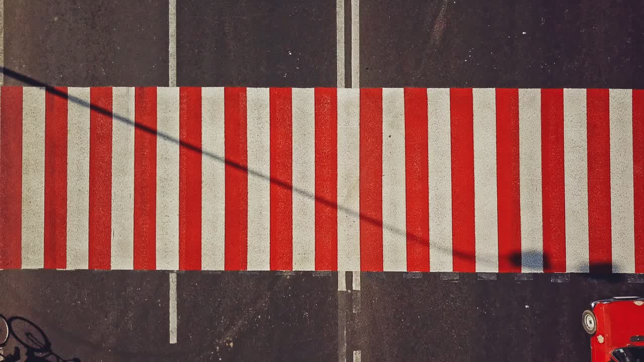 Road surface marking with red and white stripes and the cars driving on it. Pedestrian crossing on asphalt to convey official information for road safety traffic. Close-up