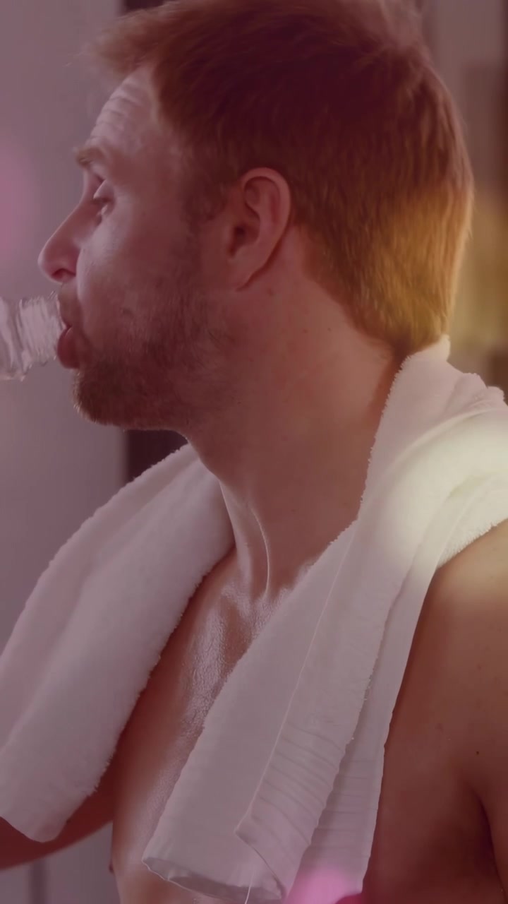 Video verticale: Uomo che sistema l'asciugamano, beve da una bottiglia, si rinfresca dopo il fitness, guarda in camera
