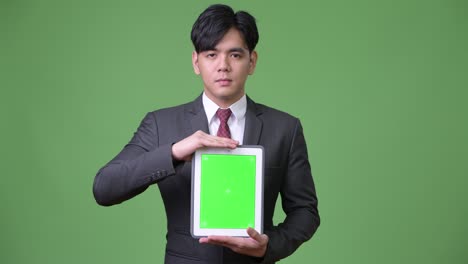 디지털 태블릿을 사용하는 젊은 잘생긴 아시아 사업가