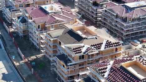 large apartment building construction progress at sunset in southern california with roofing materials laying around aerial dolly 60fps