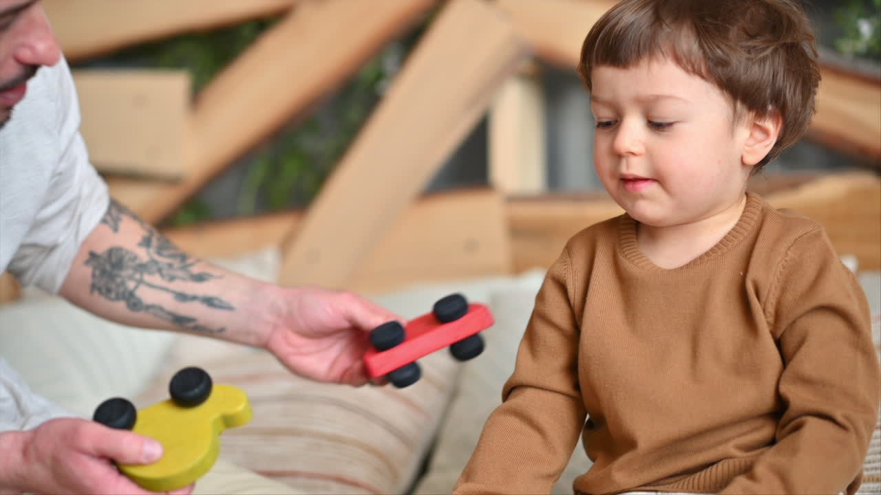 Padre che gioca con suo figlio con coloratissimi giocattoli ecologici in legno sul letto