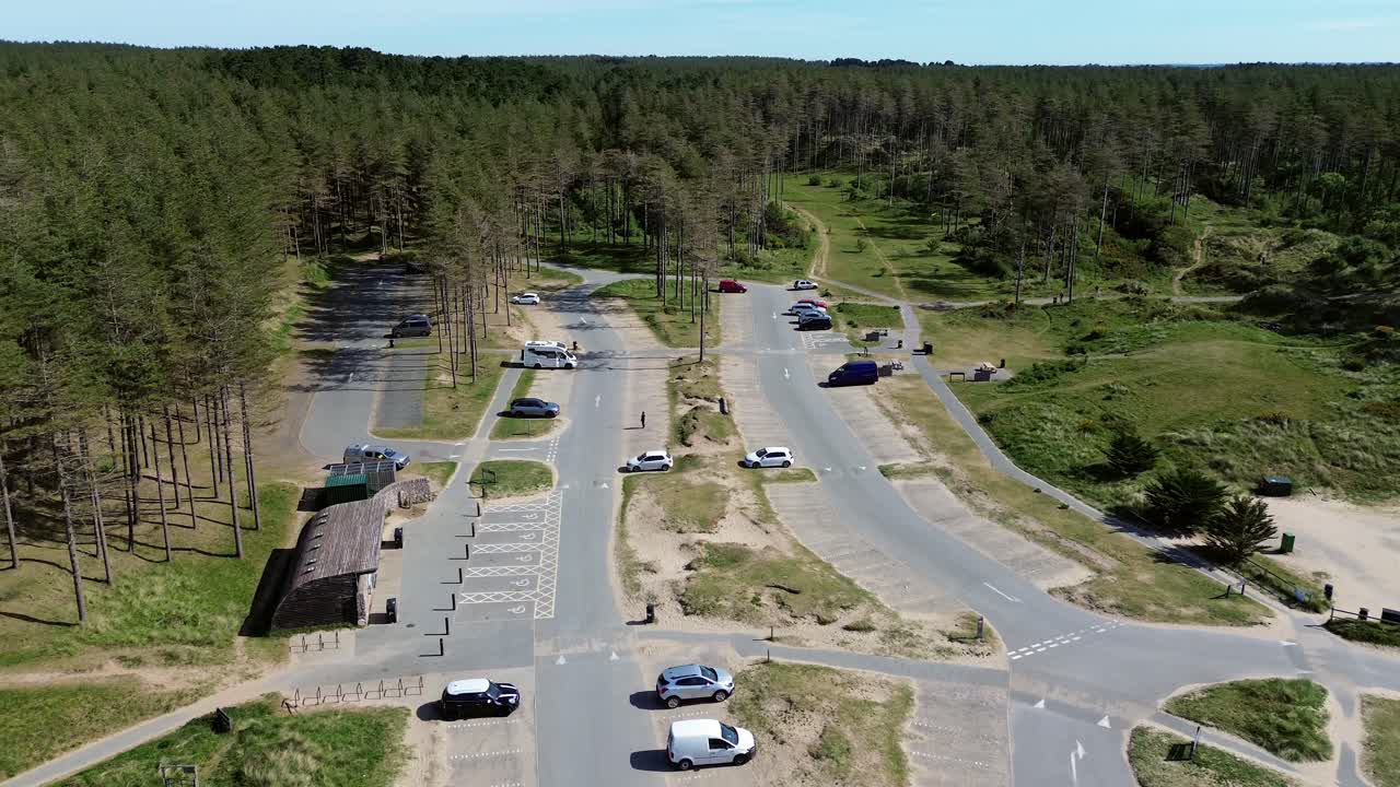 Newborough forest beach car park aerial view over sunny woodland pine trees visitors parking