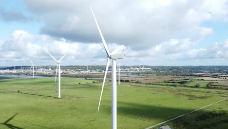 aerial view flying around renewable energy wind farm wind turbines spinning on british countryside slow descent