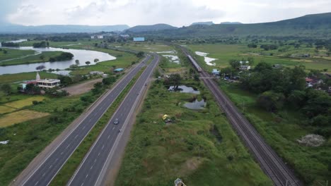 Aerial-view-of-Indian-Railway-Track-and-Indian-Highway-running-parallel-in-one-shot-with-Cargo-Freight-Train-and-Locomotive-Passing