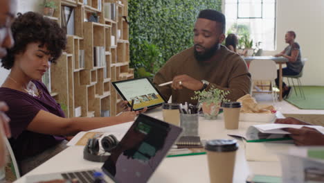 Gente-De-Negocios-Afroamericana-Reuniéndose-Con-Un-Equipo-De-Diseño-Gráfico-Creativo-Intercambiando-Ideas-De-Marketing-Líder-De-Equipo-De-Negocios-Usando-Tecnología-De-Tableta-En-La-Sala-De-Juntas-De-La-Oficina-Estrategia-Para-Compartir