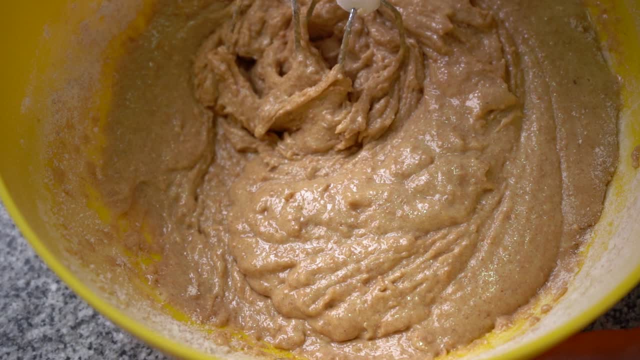 mezclando harina integral en un tazón usando una batidora eléctrica de mano - haciendo pastel de zanahoria