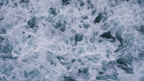 slow motion top-down shot of waves crashing along the beach creating patterns