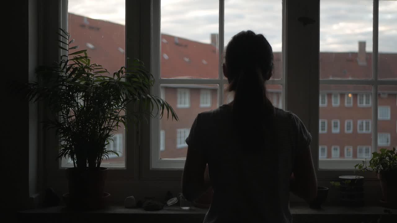 Bored, listless woman in front of apartment window in early morning