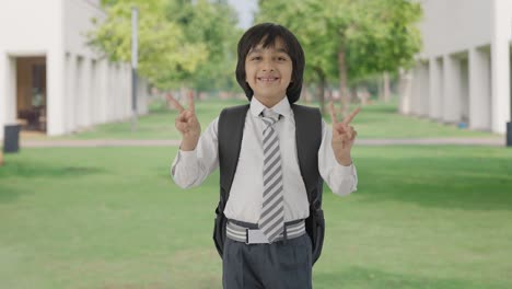 niño de escuela indio feliz mostrando el signo de la victoria