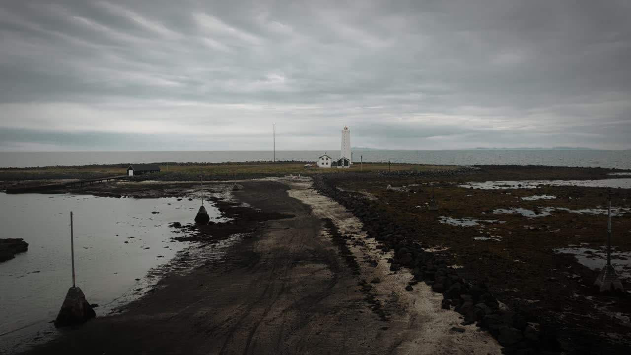 sendero aéreo de playa que conduce al faro en la isla de grotta, reykjavik, islandia, paisaje oscuro nublado y de mal humor, volando hacia arriba