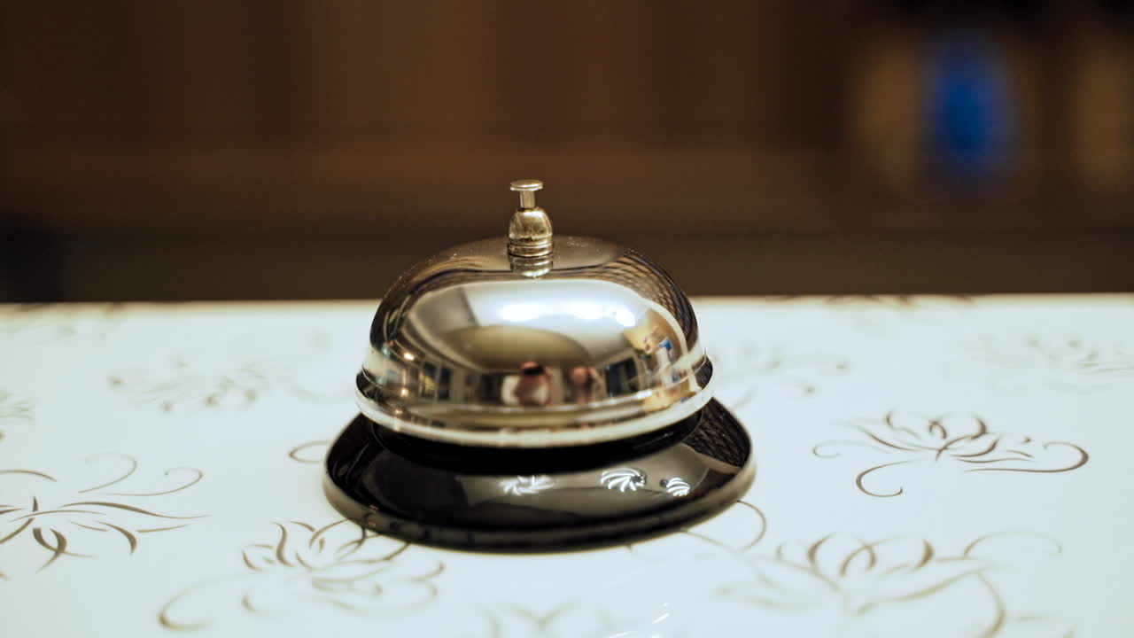 Service bell vintage with hand. Close up view of hand on golden service bell at reception desk in hotel