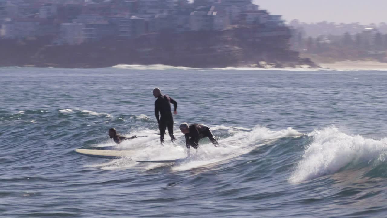 los surfistas mayores atrapan una ola en manly beach, australia