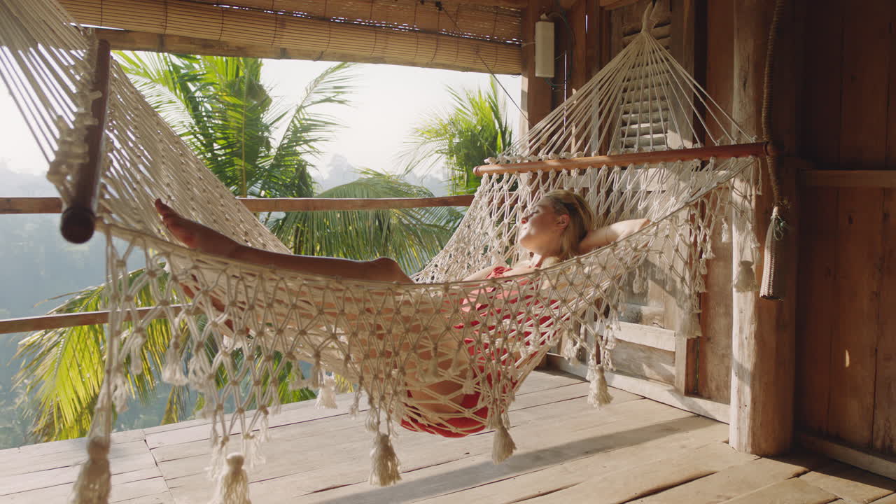 hermosa mujer en hamaca disfrutando de un estilo de vida cómodo de vacaciones en un complejo vacacional balanceándose pacíficamente en un perezoso día de verano en una cabaña de paraíso tropical
