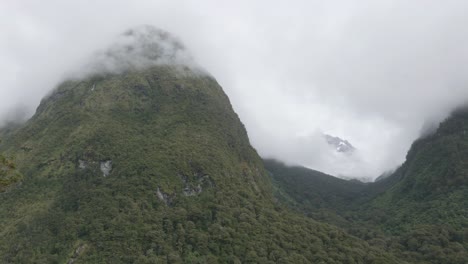 Mountain-peaks-and-forest-in-between-clouds-in-Fiordland,-New-Zealand