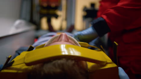 paramedic ambulance in gloves examining patient on stretcher