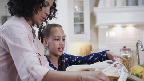 happy biracial father, mother, son and daughter unpacking shopping in kitchen, slow motion