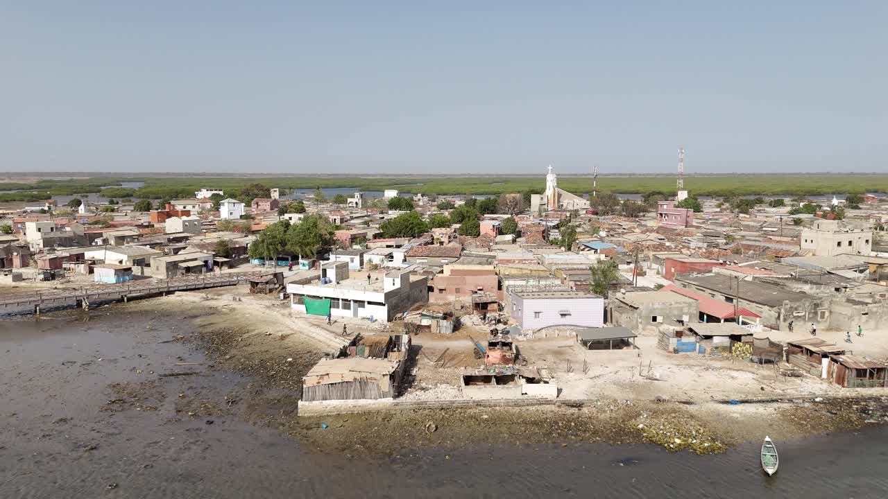 Drone aerial of Joal Fadiouth village in Senegal, showing traditional houses, coastline and daily life near the famous shell island cemetery