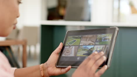 african american woman examines a tablet displaying cctv security footage at home