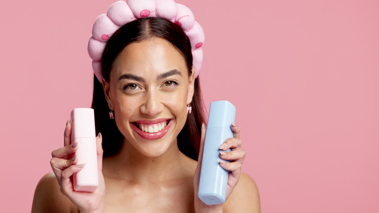 Mujer sosteniendo productos para el cuidado de la piel con un fondo rosa