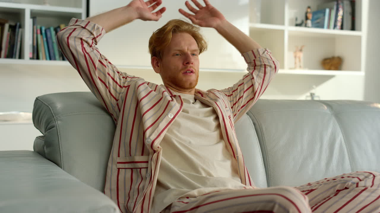 게으른 남자가 피자마를 입고 주말을 즐긴다. 린저 매니저는 집에서 소파에 누워 있다.