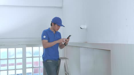 hombre asiático técnico trabajador en una escalera uso de teléfono móvil control de seguridad cámara de cctv