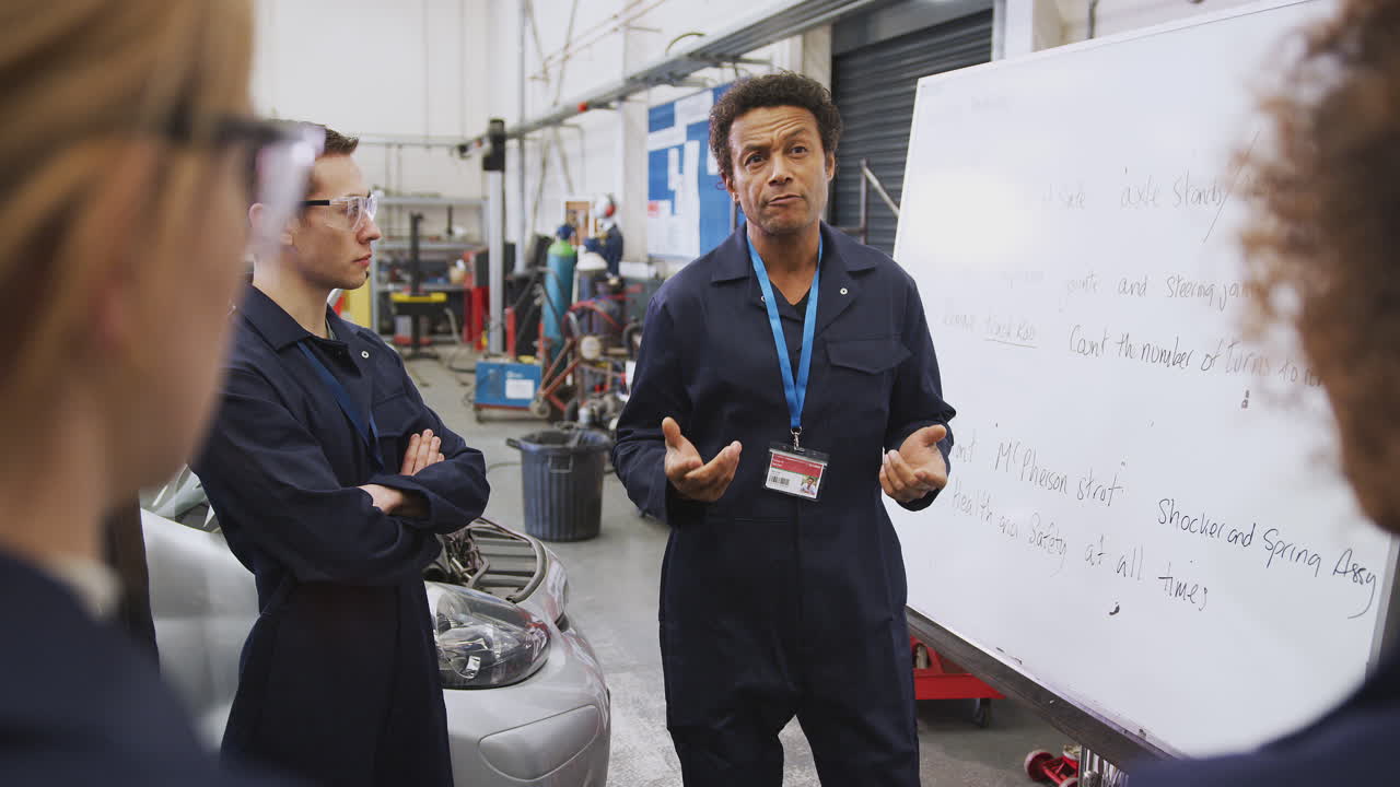 tutor masculino por pizarra con estudiantes que enseñan aprendizaje de mecánico de automóviles en la universidad