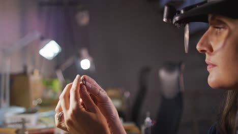 cerca de las manos de una joyera caucásica con gafas, comprobando joyas en el taller