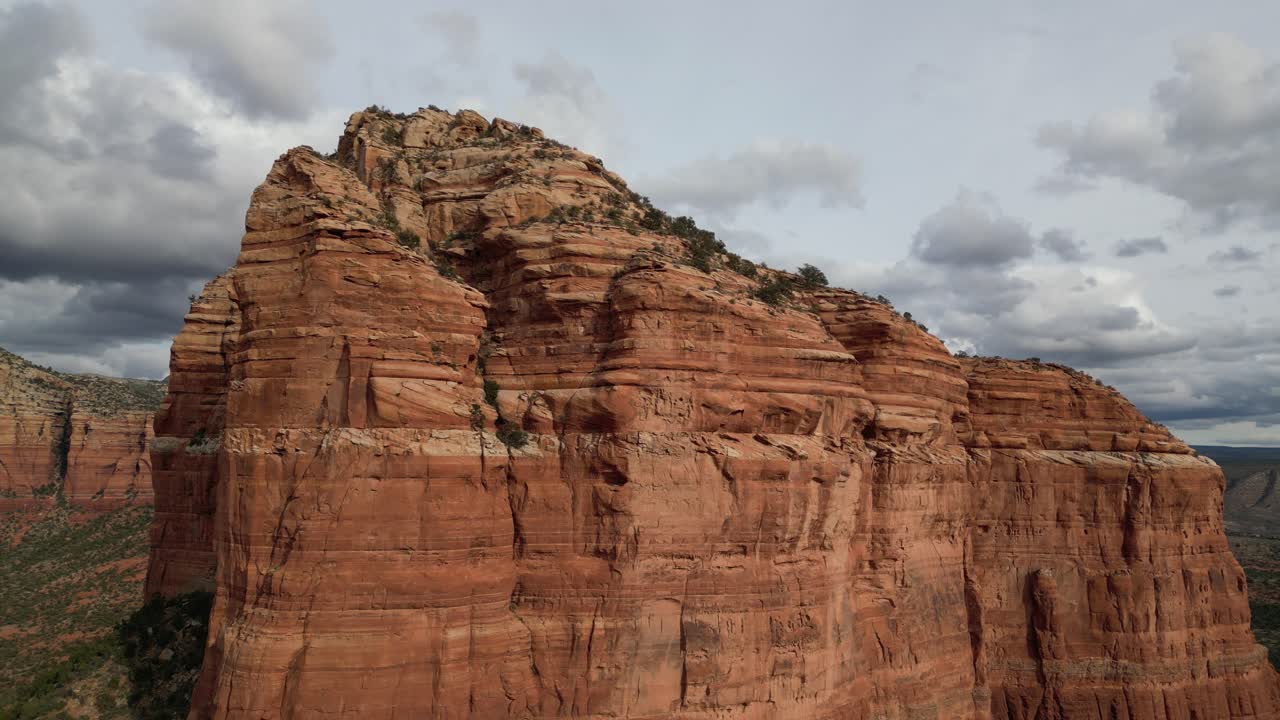 Aerial drone footage of Courthouse Butte in Sedona, Arizona, highlighting towering red sandstone formation surrounded by desert landscape, cliffs, and scenic southwestern terrain under clear skies