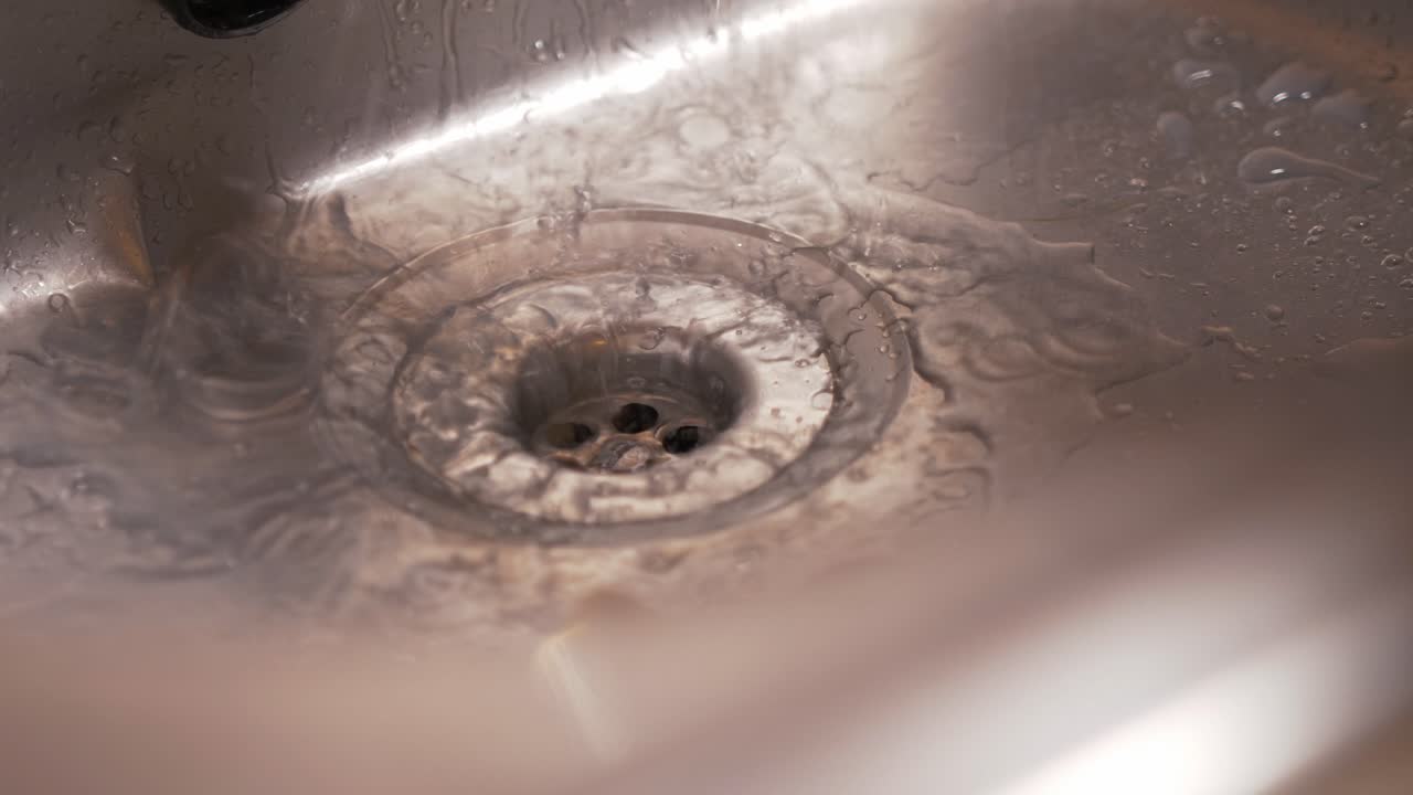 Soapy water flows down the sink drain