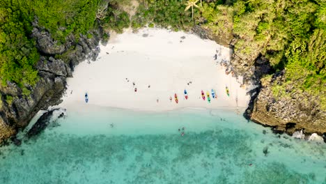 drone shot of nui beach in koh phi phi islands with people on kayaks and longtail boats