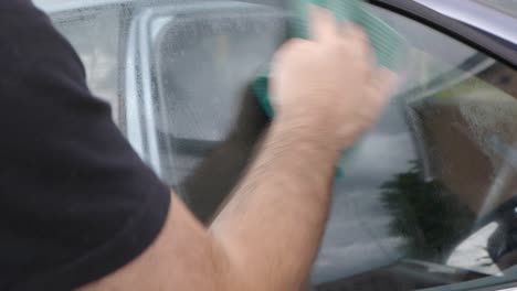 Cleaning-car-winow-with-green-cloth