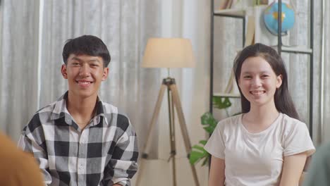 close up of asian boy and girl smiling to camera while discussing with friends at home