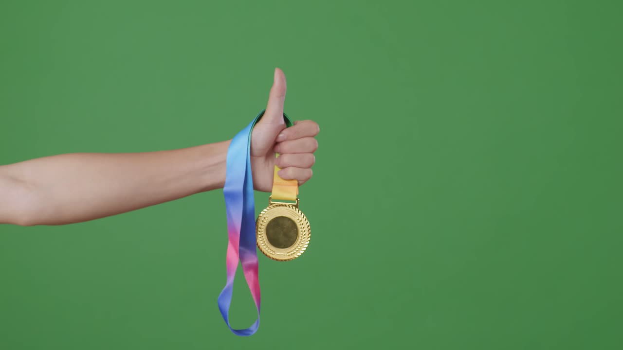 mano sosteniendo una medalla de oro con el pulgar hacia arriba