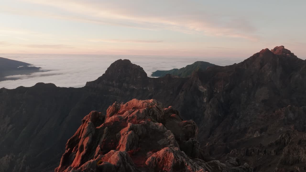 Golden light warms the textured ridge formations at Pico do Arieiro, Madeira, with layered cliffs and a distant peak on the horizon.